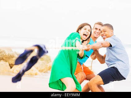 Young people pulling rope on beach Stock Photo