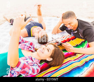 Young people lying on blanket, using technology Stock Photo