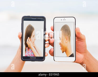 Hands holding smart phones with pictures of young people Stock Photo