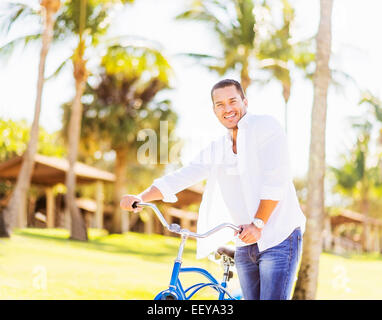 USA, Florida, Jupiter, Man with bicycle with palm trees in background Stock Photo