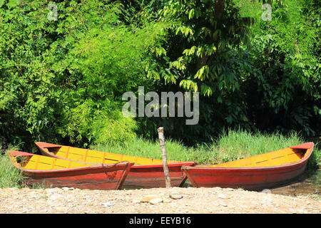 Red-yellow-orange colored wooden rowboats stranded on the shore of the 4.43 km2-784 ms.high Phewa tal-lake at the foot of Ananda Stock Photo