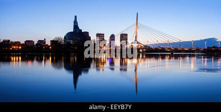 Canada, Manitoba, Winnipeg, Illuminated skyline reflecting in calm Assiniboine River Stock Photo