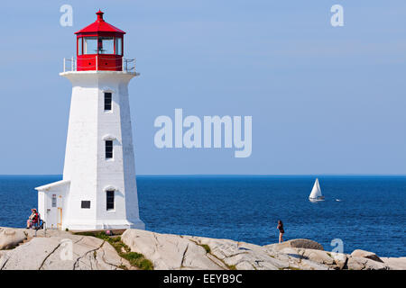 Canada, Nova Scotia, Peggy's Cove, Peggy's Point Lighthouse against sea with lone sailboat Stock Photo