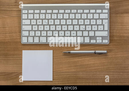 Modern keyboard a memo and a pen on a wooden Desktop Stock Photo