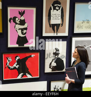 London, UK. 23 January 2015. A Bonhams employee looks at the Banksy prints from the Steve Lazarides collection. Included among the collection of iconic prints are Flower Thrower (2003), Rude Copper (2002), and Christ With Shopping Bags (2004), each estimated at £8,000-12,000. Bonhams auction house previews items from the 'Founded 1793' contemporary art auction taking place on 28 January 2015. The sale includes a collection of 30 Banksy prints owned by the English gallery owner, Steve Lazarides, and a ukulele decorated by Damien Hurst. Photo: Bettina Strenske Stock Photo