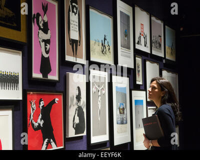 London, UK. 23 January 2015. A Bonhams employee looks at the Banksy prints from the Steve Lazarides collection. Included among the collection of iconic prints are Flower Thrower (2003), Rude Copper (2002), and Christ With Shopping Bags (2004), each estimated at £8,000-12,000. Bonhams auction house previews items from the 'Founded 1793' contemporary art auction taking place on 28 January 2015. The sale includes a collection of 30 Banksy prints owned by the English gallery owner, Steve Lazarides, and a ukulele decorated by Damien Hurst. Photo: Bettina Strenske Stock Photo