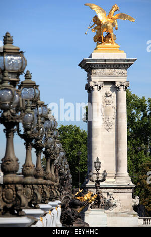 Ornate renaissance street lamps on the famous Pont Alexandre III bridge in central Paris with golden gateway statue Stock Photo