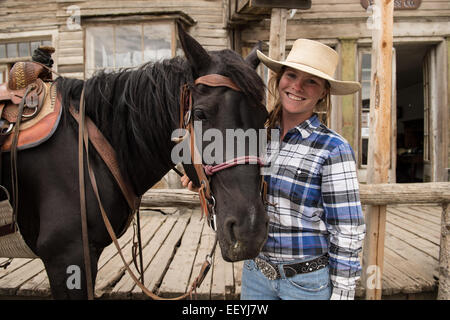 Virginia City Overland Stage employee Mariah Fredrickson waits with her horse Oakley for a stage coach tour to return outside the company’s office in Virginia City, Montana (Photo by Ami Vitale) Stock Photo