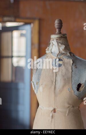 An old dress form mannequin in an abandoned clothing factory. Stock Photo