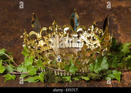 Royal display of a medieval golden crown on wood, ivy and moss Stock Photo