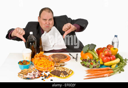 Overweight man sitting at a table full of food Stock Photo