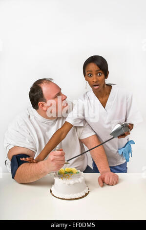Nurse trying to stop overweight man from eating cake Stock Photo