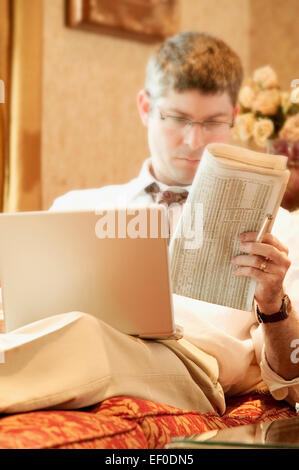 Man working on his laptop while relaxing on the sofa Stock Photo