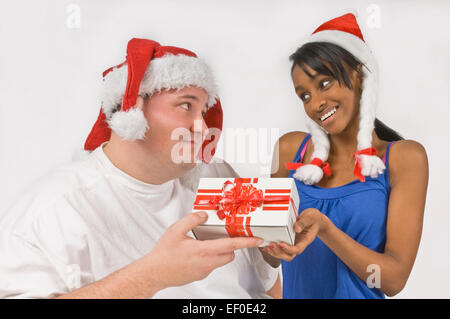 Overweight man giving Christmas present to slim woman Stock Photo