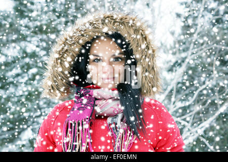 Beautiful young woman with red winter coat in heavy snow, filter Stock Photo