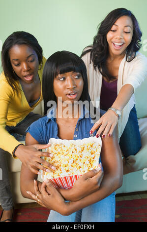 Three friends eating popcorn Stock Photo