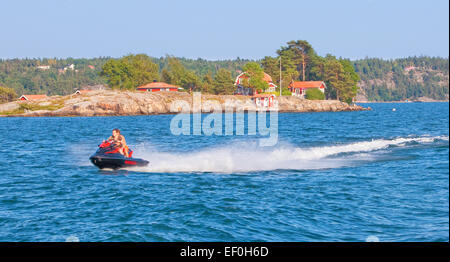 Sweden, Stockholm - Men riding personal watercraft jet ski in archipelago. Stock Photo