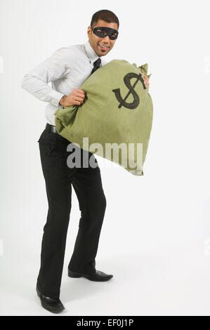 Man wearing mask and holding bag of money Stock Photo