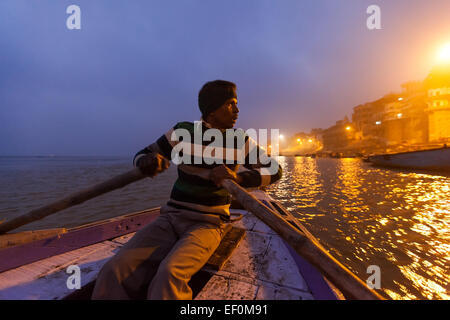 VARANASI, INDIA - 05 JANUARY, 2015 : A man rowing a wooden tourist boat on the Ganges just before sunrise. Stock Photo