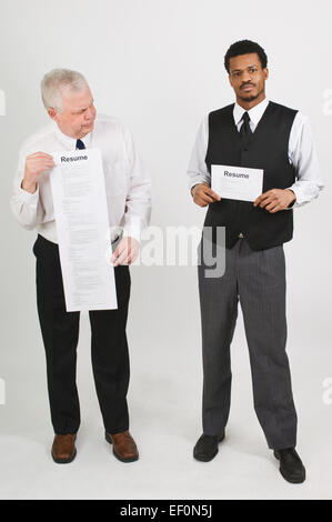 Two men holding contrasting resumes Stock Photo