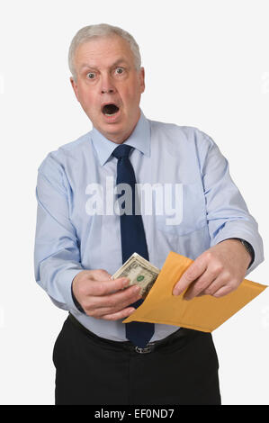 Surprised businessman putting money in an envelope Stock Photo