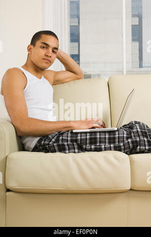 Man using laptop while sitting on couch Stock Photo