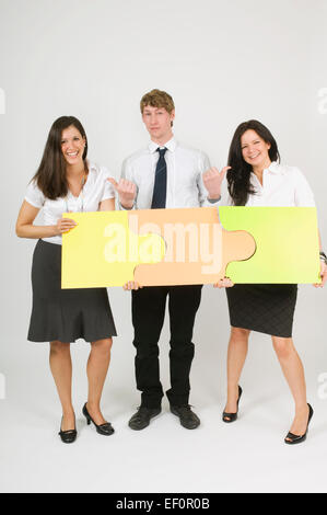 Three people putting puzzle pieces together Stock Photo