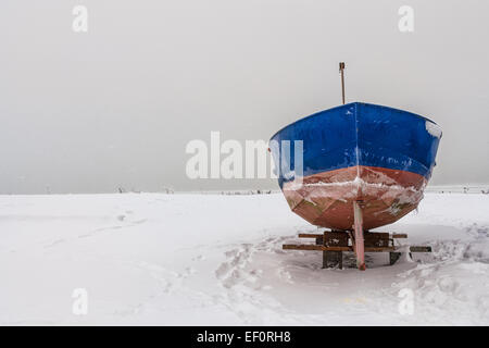 A fishing boat on shore of the Baltic Sea in winter.