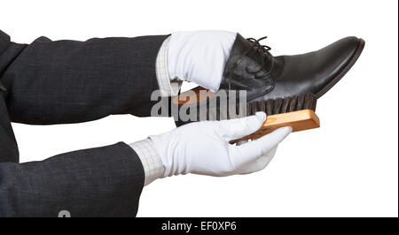 Shoeshiner in white gloves brushing black shoe by brush isolated on white background Stock Photo