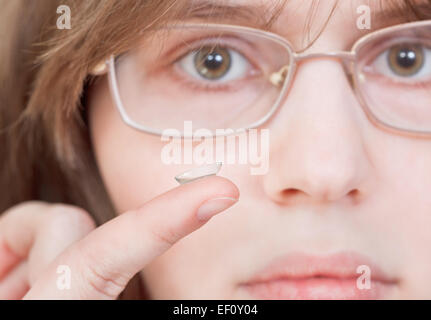 girl with glasses holds contact lens on your finger near the eyes Stock Photo