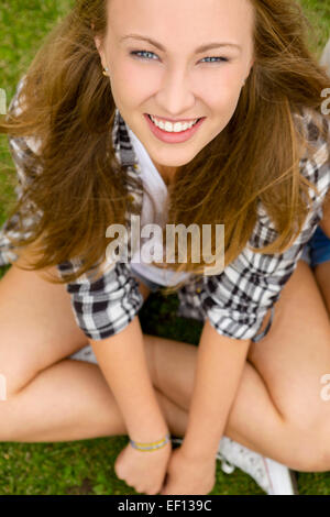 Happy and beautiful teenage girl sitting on the grass Stock Photo
