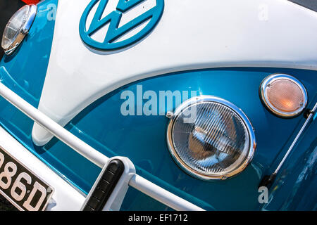 Front section of a Volkswagen camper van.  Blue and white image shows the round headlight and part of the VW logo badge. Stock Photo