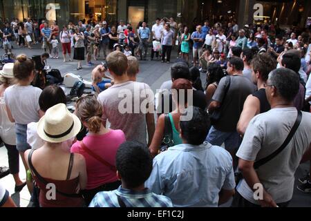 A busker musician,with a crowd of people watching the performer on ...