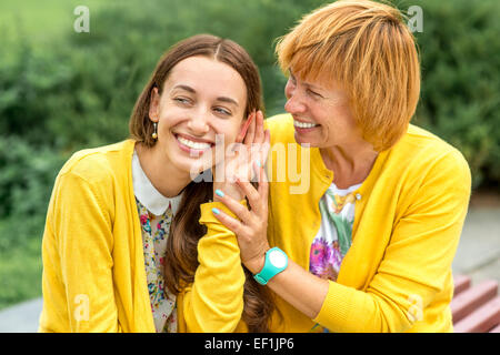 Mother whispering something to her daughter in the park Stock Photo
