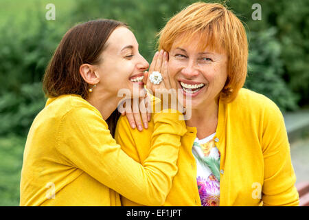 Daughter whispering something to her mother in the park Stock Photo