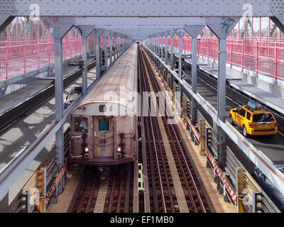 Subway train and yellow cab pass each other on the Williamsburg Bridge in New York, NY, USA - September 14, 2013. Stock Photo