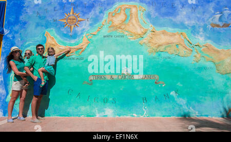 Family of four near big map of Caribbean island Turks and Caicos painted on the wall Stock Photo