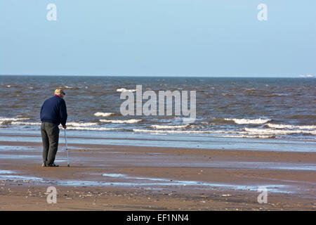 old man on beach with walking sticks looking out to sea Stock Photo