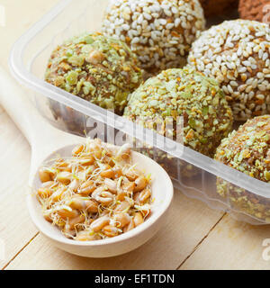 macrobiotic healthy food: balls from ground wheat sprouts with sesame and green pumpkin seeds sprinkles in plastic box; sprouted Stock Photo