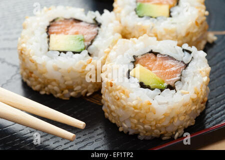 sushi rolls on black wooden plate and chopsticks Stock Photo