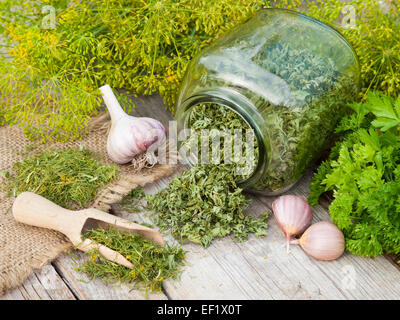 Fresh and dried chopped dill and parsley leaves on wooden plank Stock Photo