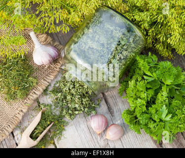 Fresh and dried chopped dill and parsley leaves on wooden rustic plank, top view. Stock Photo