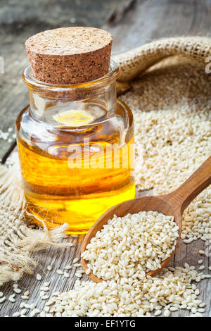 bottle of oil sesame seeds in sack on wooden rustic table Stock Photo
