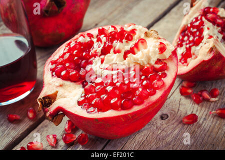 Pieces of ripe pomegranate and juice in glass on wooden rustic table Stock Photo