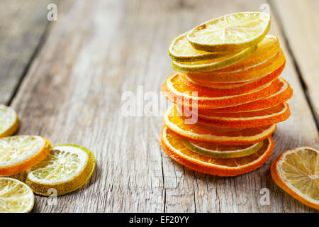 Stack of dried orange and lemon slices on old wooden table.
