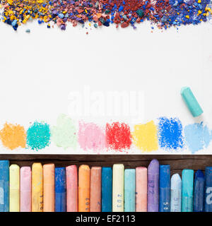 Pastel crayons and white paper sheet of sketchbook with spots of paints and pigment dust. Stock Photo