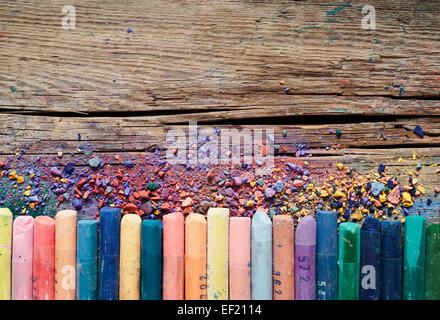 Pastel crayons and pigment dust on old wooden background. Stock Photo