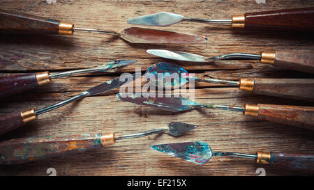 artist palette knifes on old wooden rustic table, retro stylized Stock Photo
