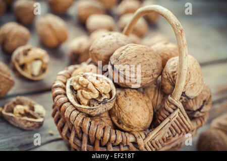 Walnuts closeup in wicker basket on old wooden rustic table. Selective focus. Stock Photo
