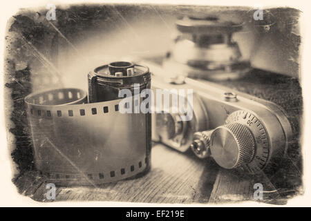 Old photo film roll and retro camera on desk. Vintage stylized photo. Stock Photo